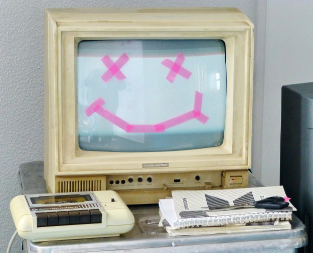 white crt tv turned on beside white remote control