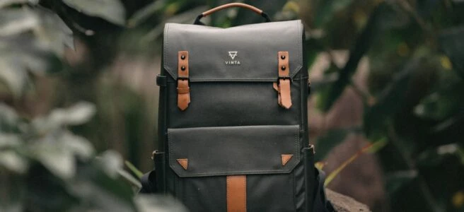 selective focus photography of black and brown leather backpack on rock